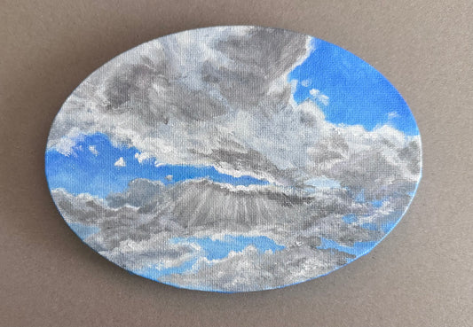 Photo of a 5in x 7in oval painting of clouds on canvas 