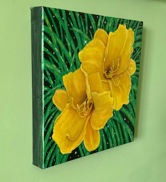 A side view of a square canvas depicting two large yellow flowers with green leaves on a dark background, hanging on a light green wall